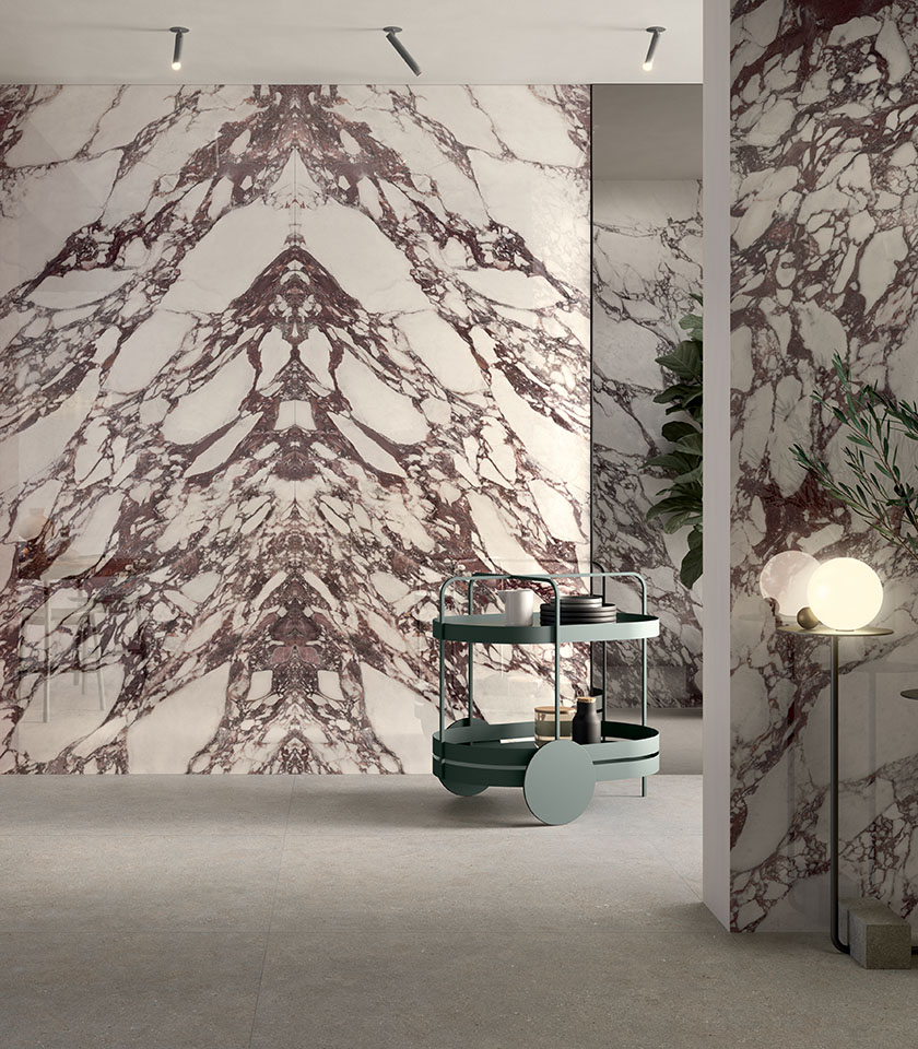 Intérieur contemporain avec de grandes surfaces effet marbre aux veines bordeaux, associées à un sol neutre et à un mobilier design.