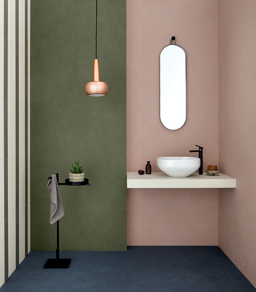 Salle de bains moderne avec murs verts et roses, surfaces épurées et détails au design minimaliste.