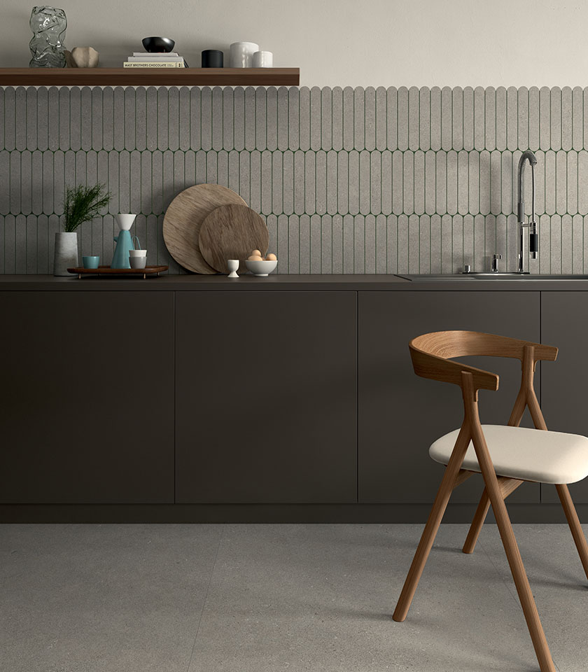Cuisine minimal chic avec sol effet béton, revêtement mural géométrique ton sur ton, mobilier sombre et détails en bois au design épuré.
