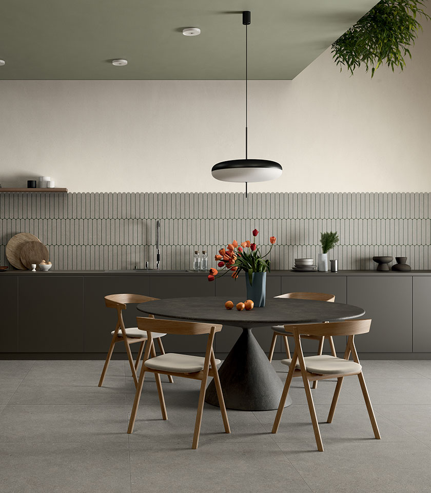 Espace repas contemporain avec table sombre et chaises en bois, sol de la collection Intense effet pierre Crete Clair et revêtement mural décoratif Pills Crete.