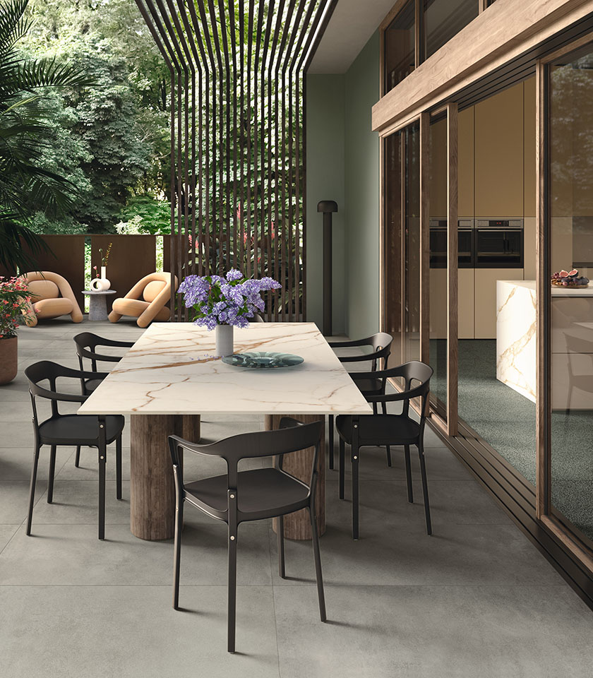 Espace repas extérieur contemporain avec sol de la collection Masterpiece effet pierre dans la teinte Master Gray, éléments Piece Alpi et table avec surface de la collection Delight effet marbre Calacatta Oro.