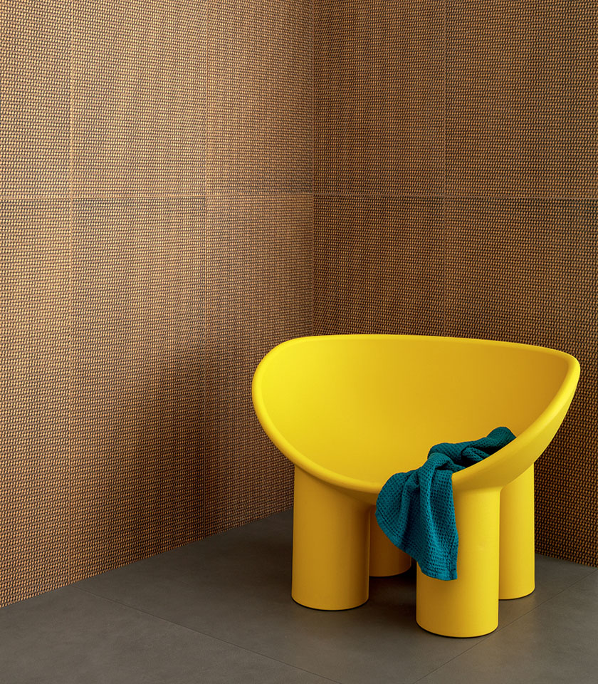 Intérieur de salle de bains contemporain avec revêtement décoratif dans les tons orange et noir, fauteuil jaune et détails textiles bleus.