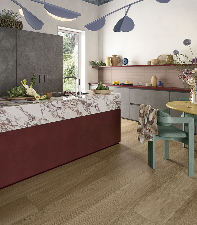 Cuisine contemporaine avec sol de la collection Biocharme effet bois dans la teinte Bark, îlot avec surface de la collection Noblesse effet marbre Arabesque, éléments de la collection Pulse dans la teinte Shadow et revêtement Pigmenti Mauve.