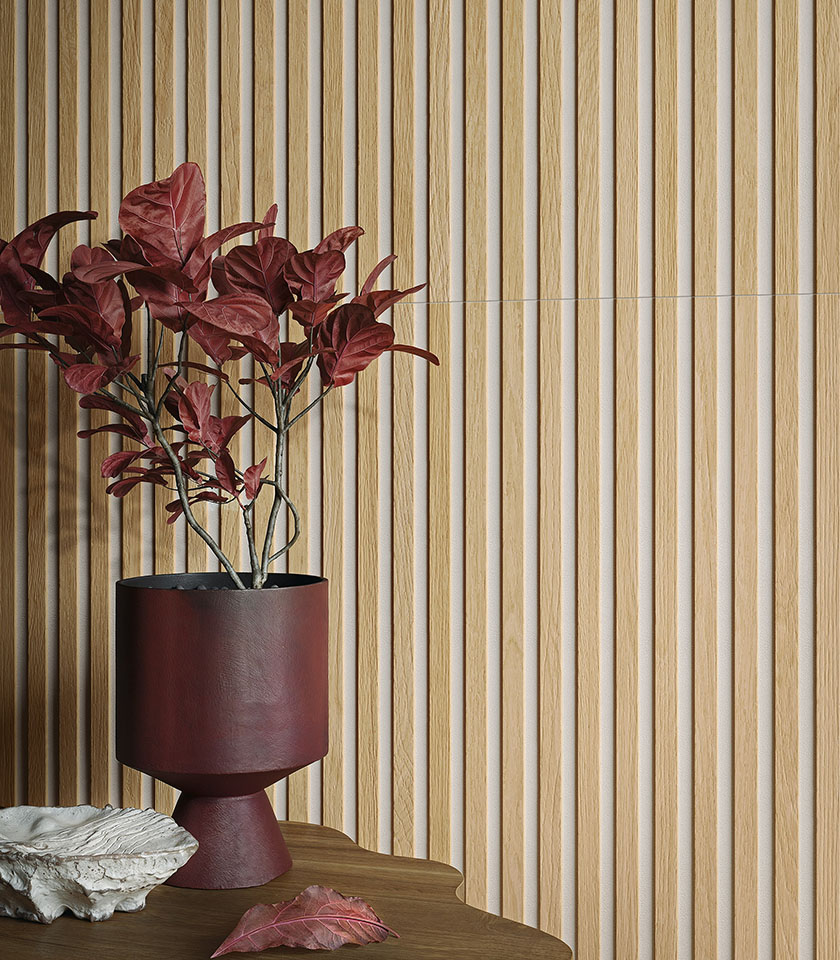 Détail d’un revêtement mural tridimensionnel effet bois clair avec vase bordeaux et composition végétale décorative.