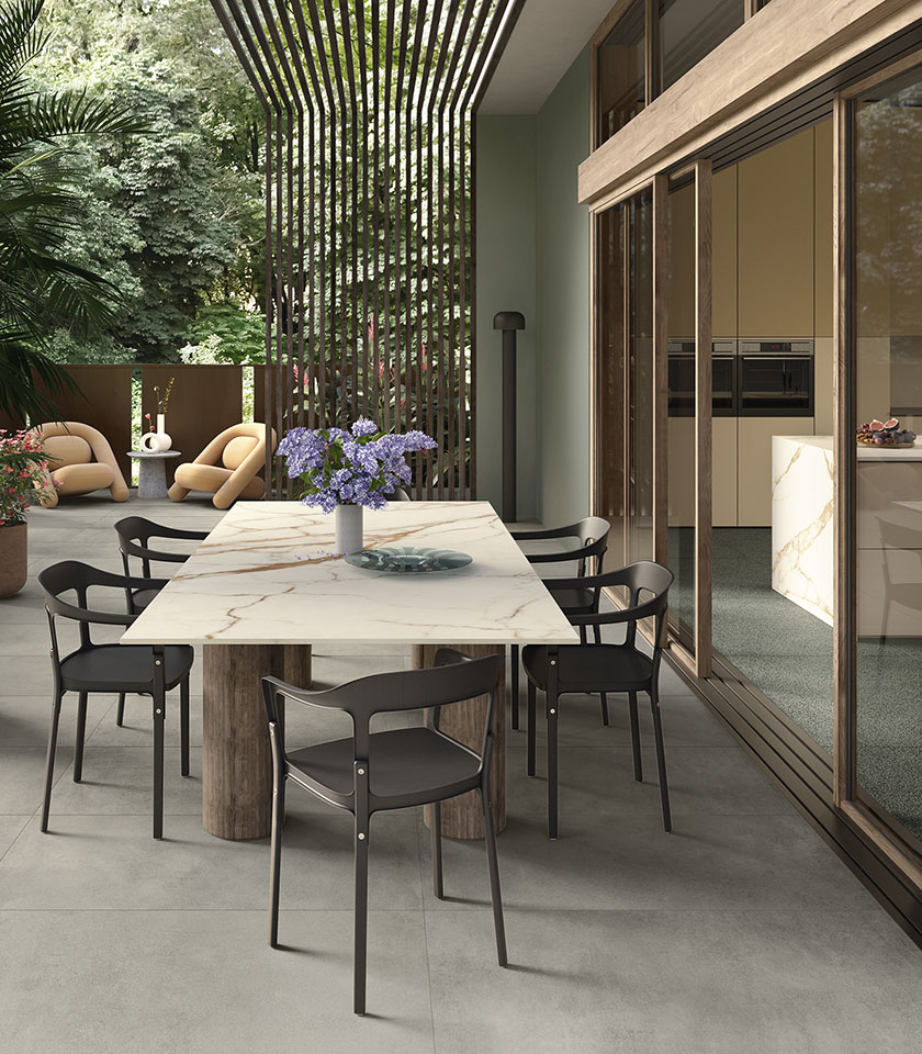 Terrasse contemporaine avec sol en grès cérame, mobilier design, grande table effet marbre et continuité harmonieuse entre intérieur et extérieur.