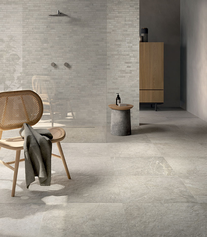 Salle de bains minimal chic avec sol effet pierre claire, revêtement mural texturé ton sur ton, douche à l’italienne et mobilier en bois au design épuré.