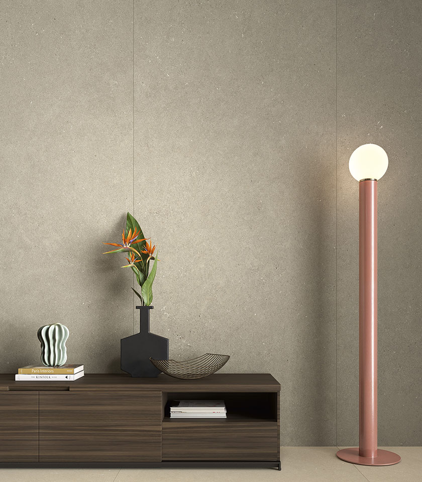 Intérieur contemporain avec revêtement mural grand format effet béton, meuble bas en bois et lampadaire décoratif.