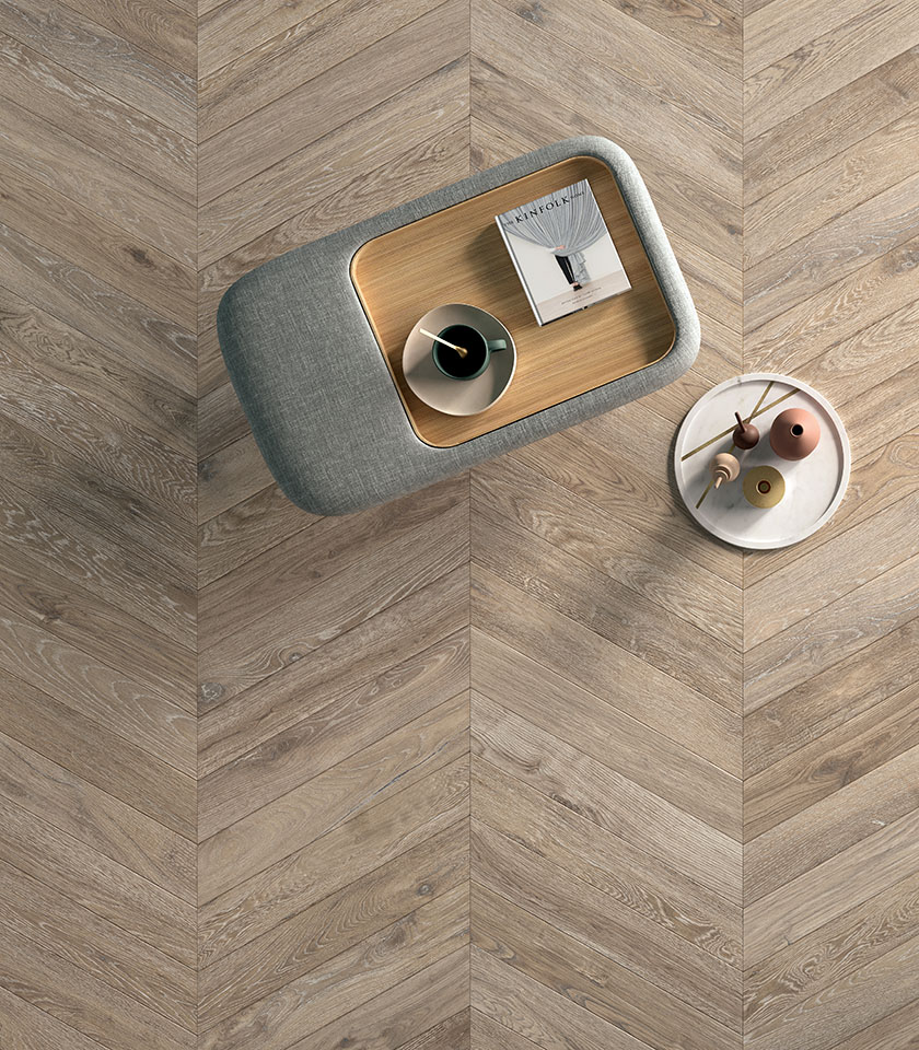 Sol en grès cérame effet bois posé en chevrons, vu du dessus avec des tables au design contemporain.