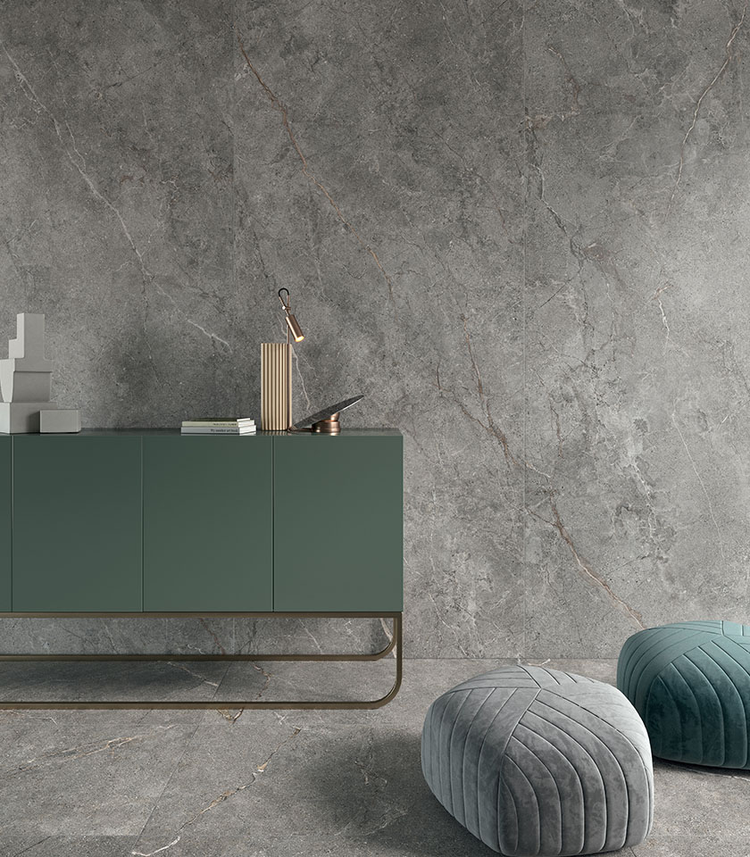 Sol en grès cérame grand format effet pierre sombre, vu du dessus avec table d’appoint, assise et accessoires décoratifs.